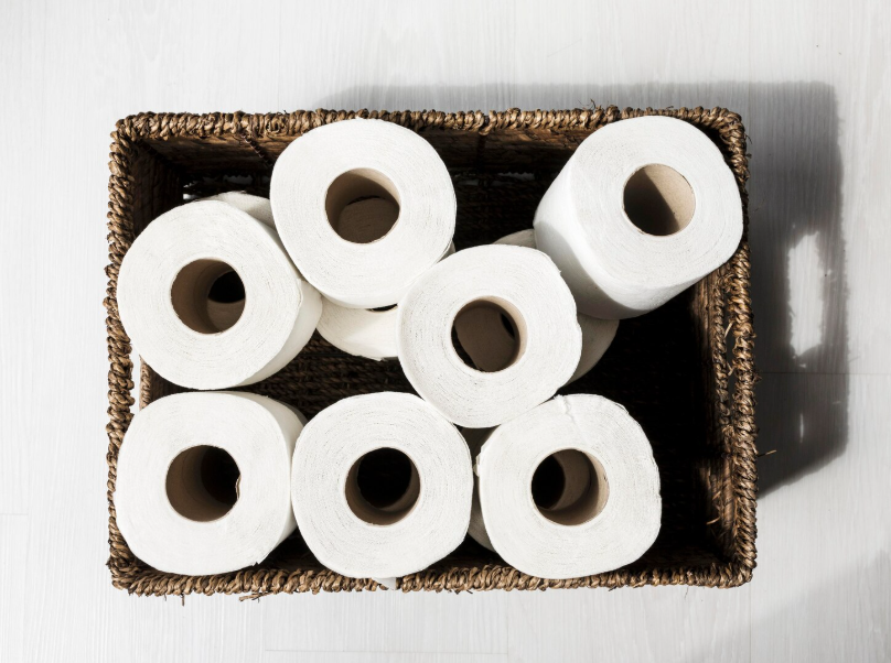 Toilet paper rolls stored in a basket showing household savings from buying in bulk.”