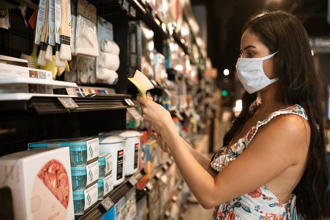 Woman shopping at a dollar store, comparing household items for quality and value.
