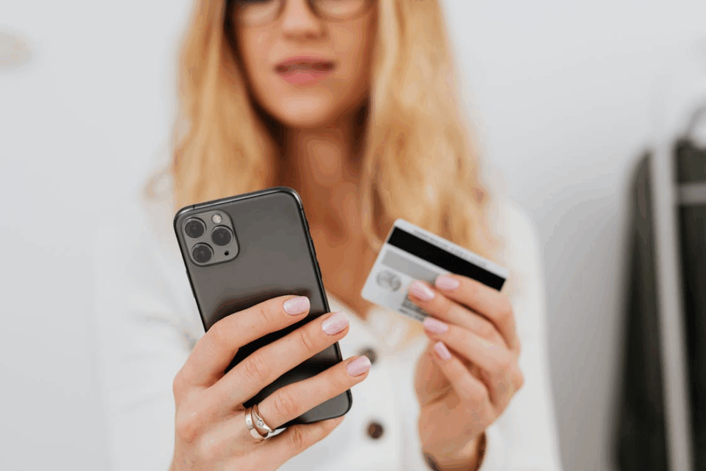 Woman holding a smartphone with a cashback app and a credit card for online shopping rewards