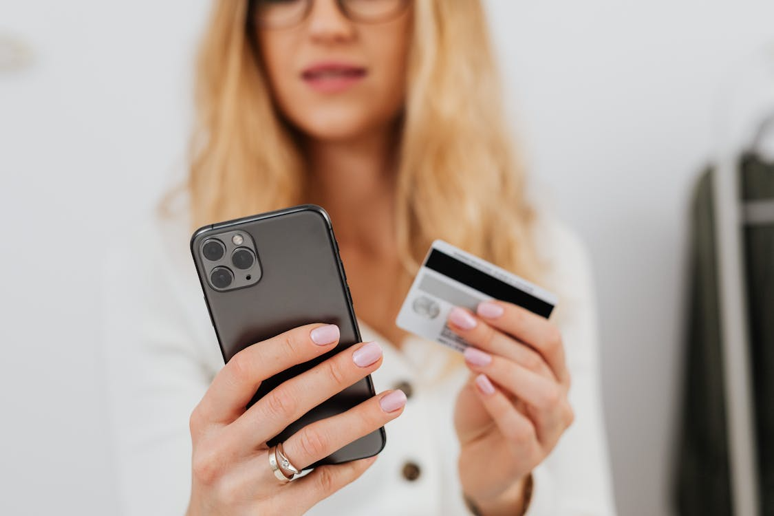 Woman holding a smartphone with a cashback app and a credit card for online shopping rewards